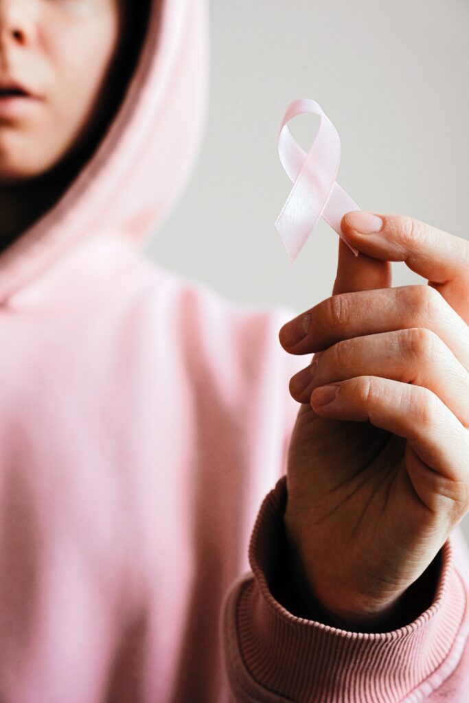 Woman-in-pink-hoodie-holding breast-cancer-ribbon